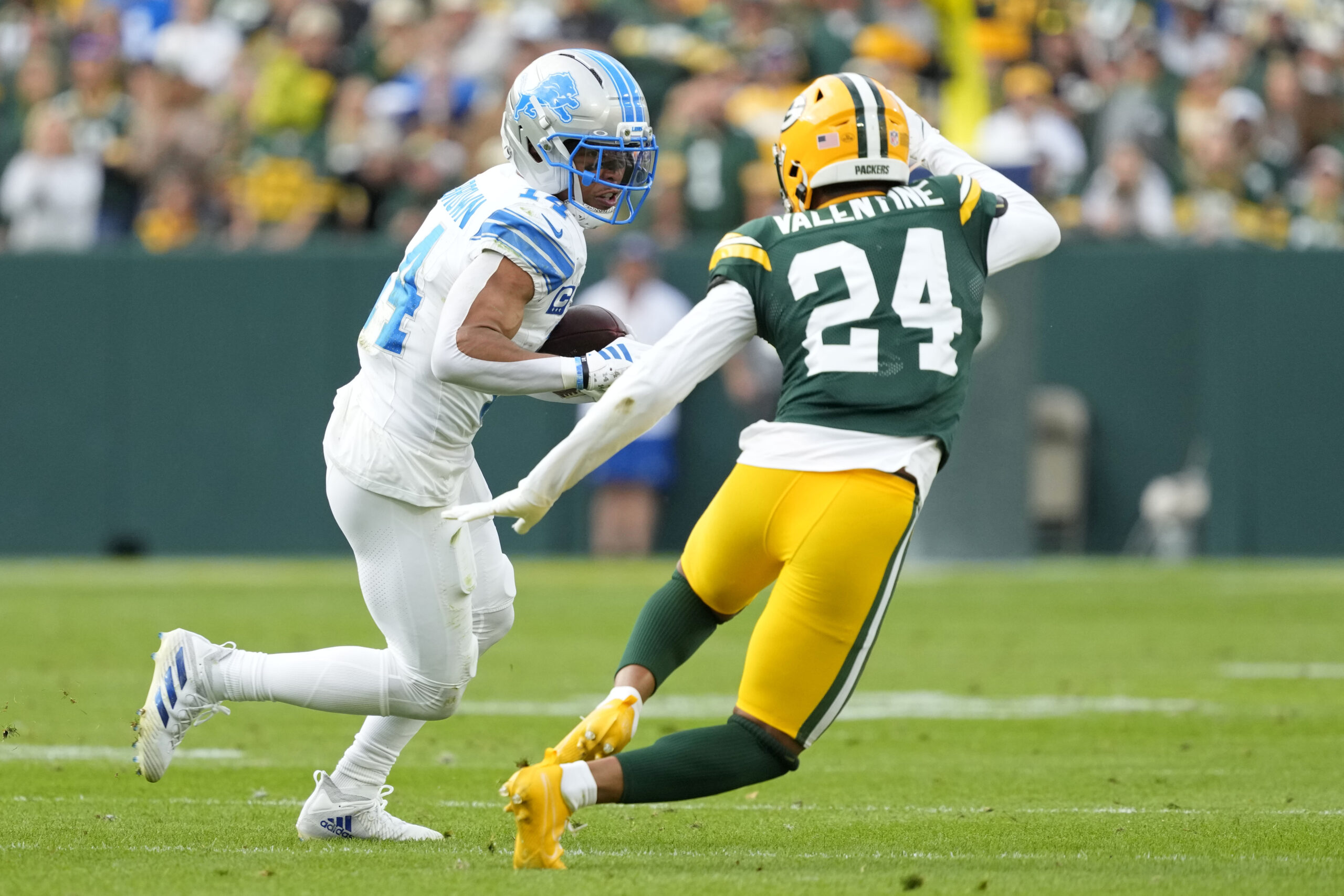 Sep 7, 2025; Green Bay, Wisconsin, USA; Detroit Lions wide receiver Amon-Ra St. Brown (14) runs with the ball after a catch against Green Bay Packers cornerback Carrington Valentine (24) during the fourth quarter at Lambeau Field. Mandatory Credit: Jeff Hanisch-Imagn Images