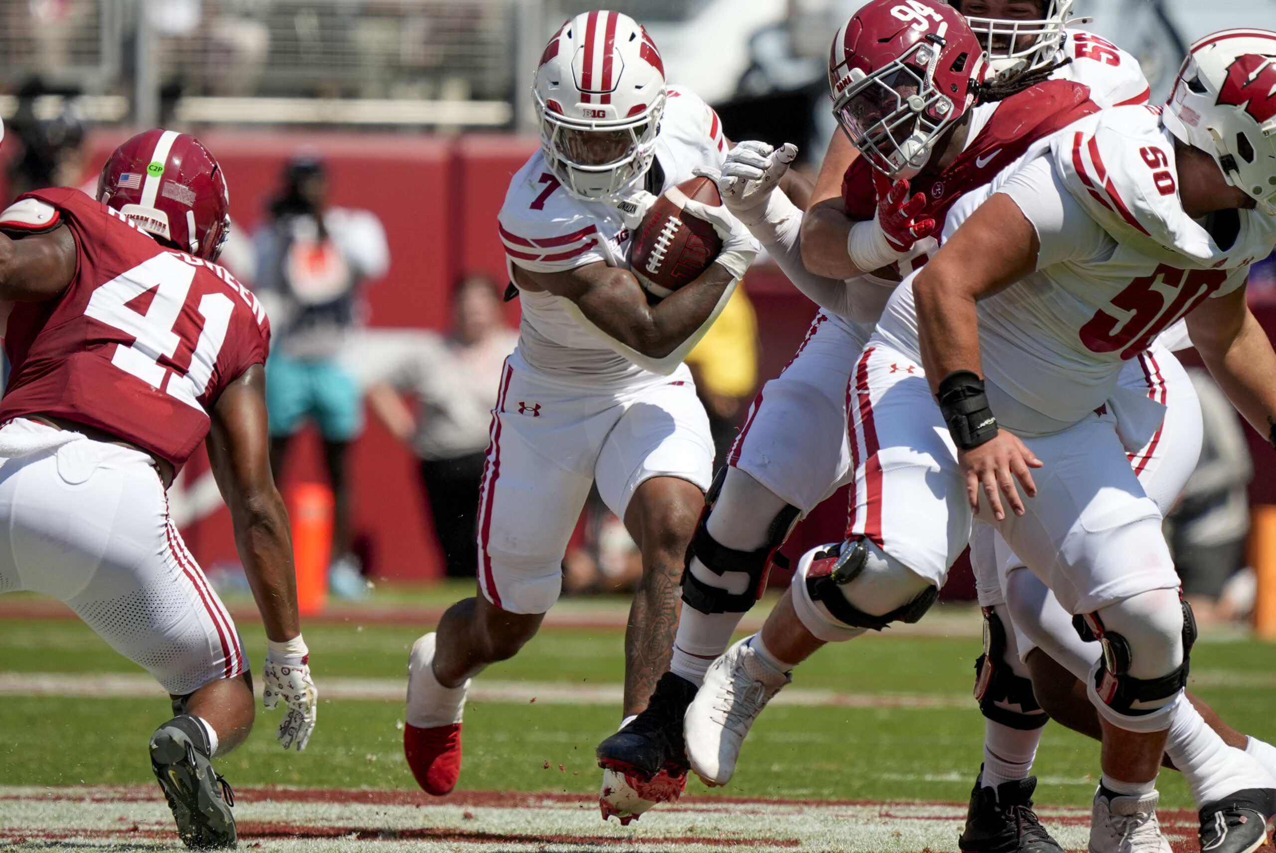 Sep 13, 2025; Tuscaloosa, Alabama, USA;  Wisconsin running back Dilin Jones (7) runs the ball between Alabama linebacker Nikhai Hill-Green (41) and Alabama defensive lineman Edric Hill (94) at Saban Field at Bryant-Denny Stadium. Mandatory Credit: Gary Cosby-USA TODAY Network via Imagn Images