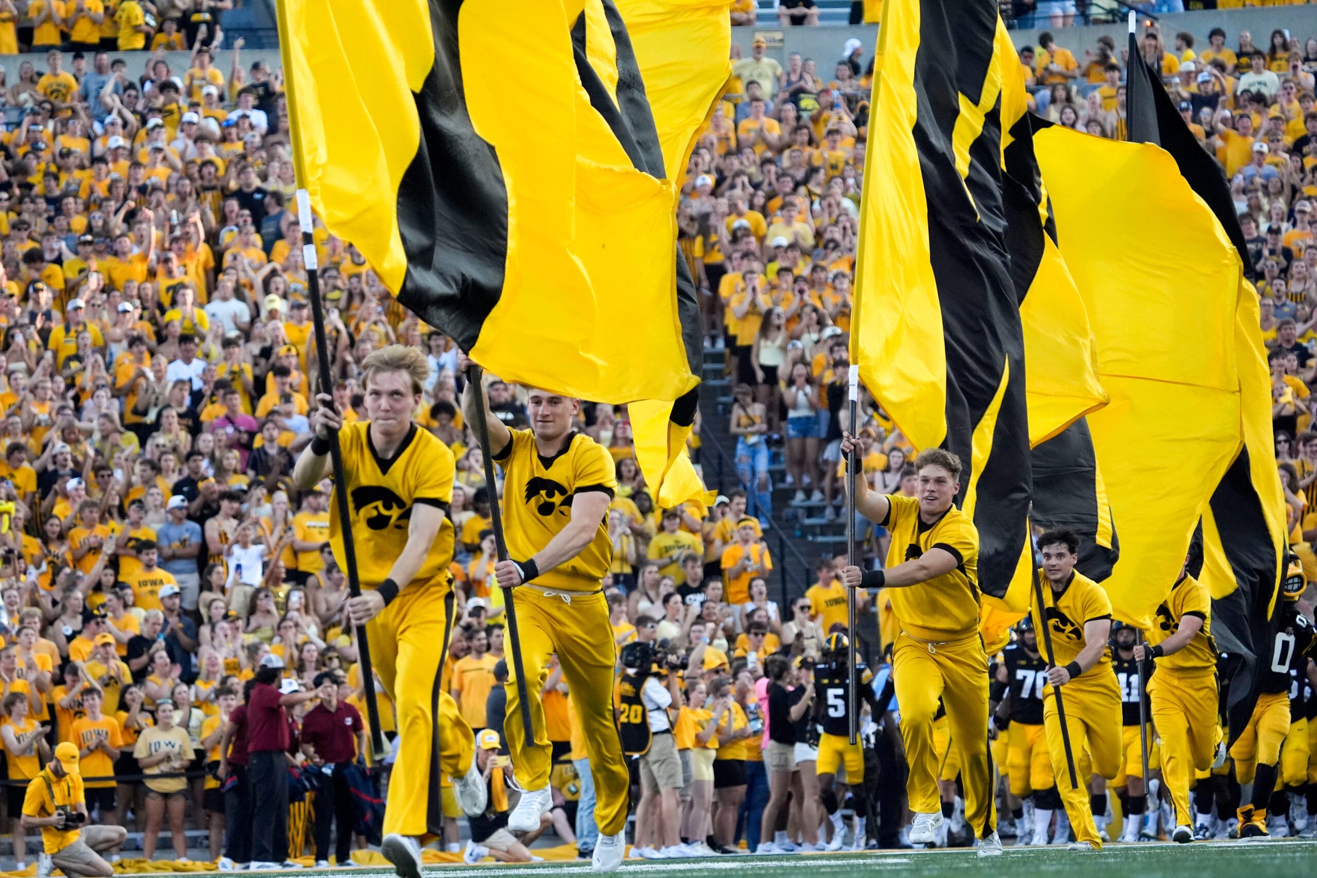 The Iowa Hawkeyes spirit squard runs flags across the field as the players swarm onto the field ahead of the football game against the Massachusetts Minutemen Sept. 13, 2025 at Kinnick Stadium in Iowa City, Iowa.