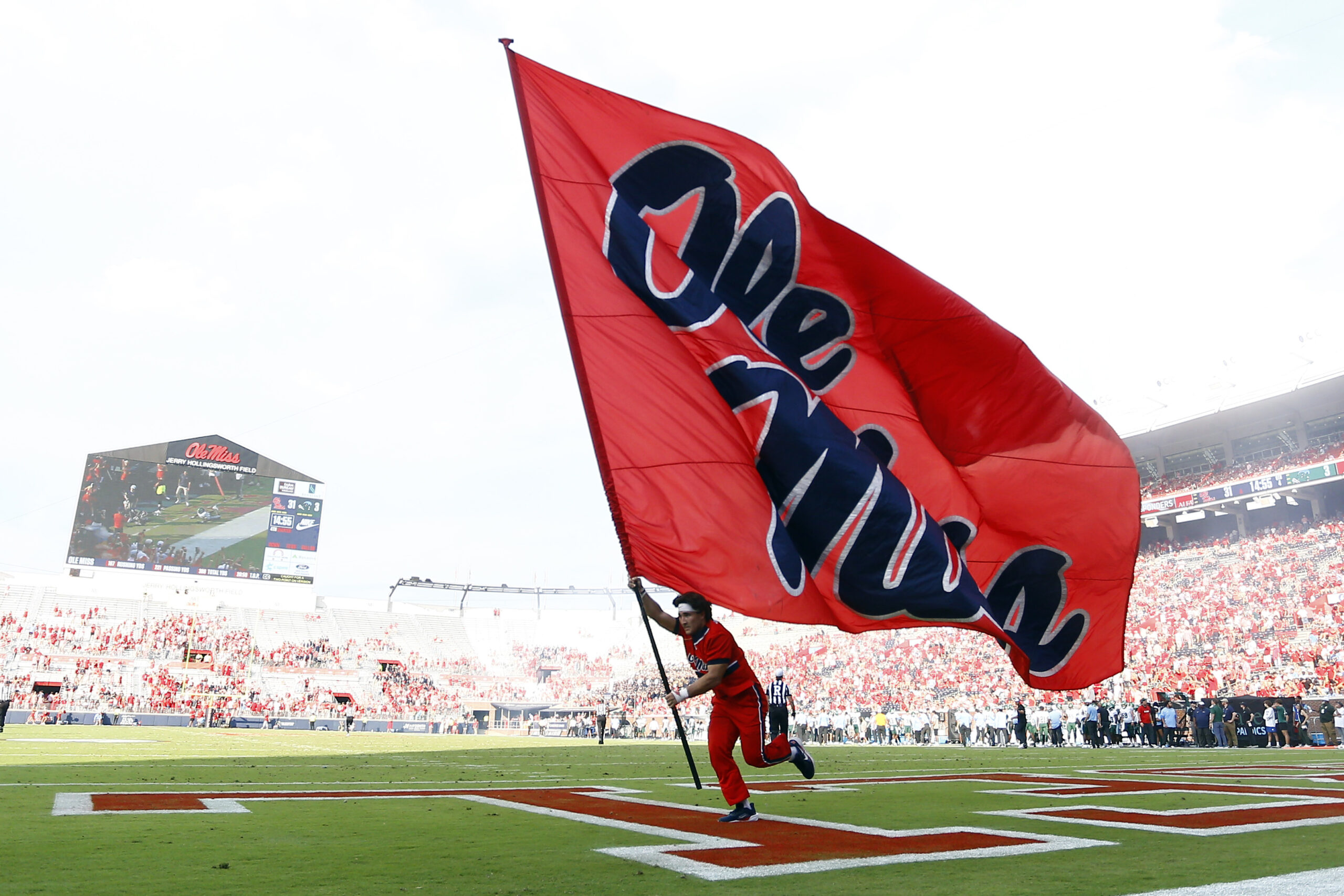 Sep 20, 2025; Oxford, Mississippi, USA; Mississippi Rebels cheerleader run an Ole Miss flag through the end zone after a touchdown during the fourth quarter against the Tulane Green Wave at Vaught-Hemingway Stadium. Mandatory Credit: Petre Thomas-Imagn Images