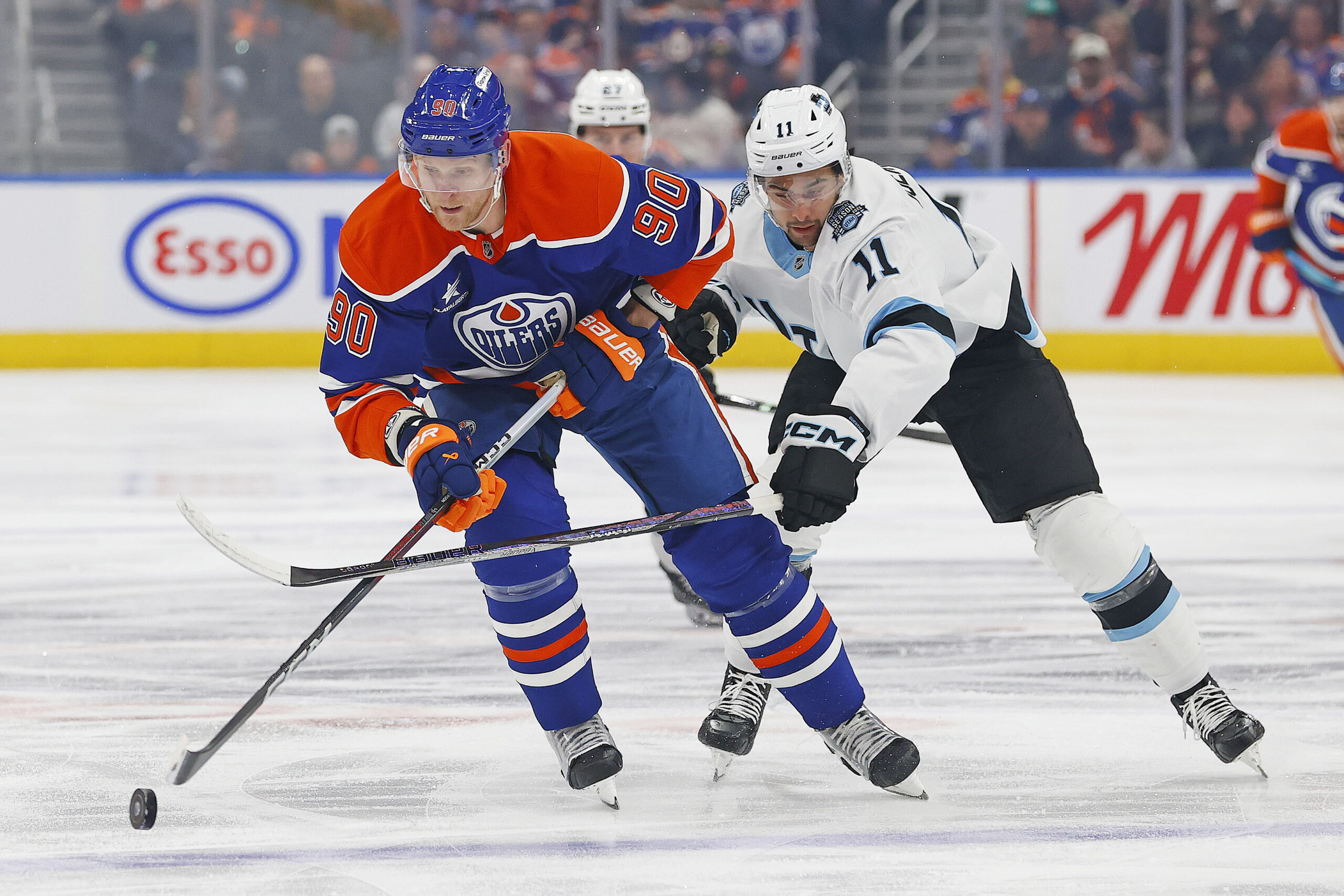 Mar 18, 2025; Edmonton, Alberta, CAN; Utah Hockey Club froward Dylan Guenther (11) tries to knock the puck away from Edmonton Oilers forward Corey Perry (90) during the first period at Rogers Place. Mandatory Credit: Perry Nelson-Imagn Images