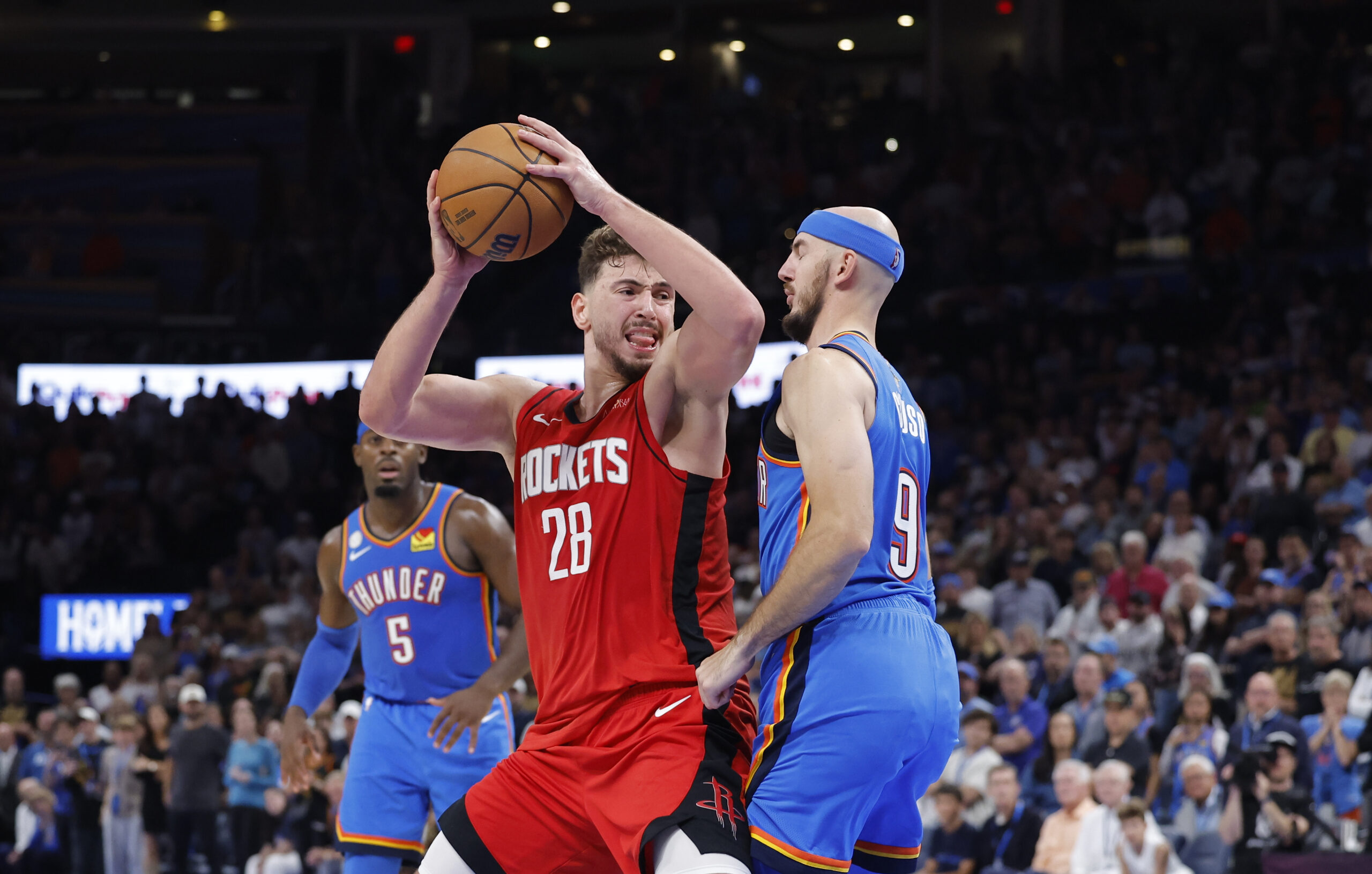 Oct 21, 2025; Oklahoma City, Oklahoma, USA; Houston Rockets center Alperen Sengun (28) drives against Oklahoma City Thunder guard Alex Caruso (9) during overtime at Paycom Center. Mandatory Credit: Alonzo Adams-Imagn Images