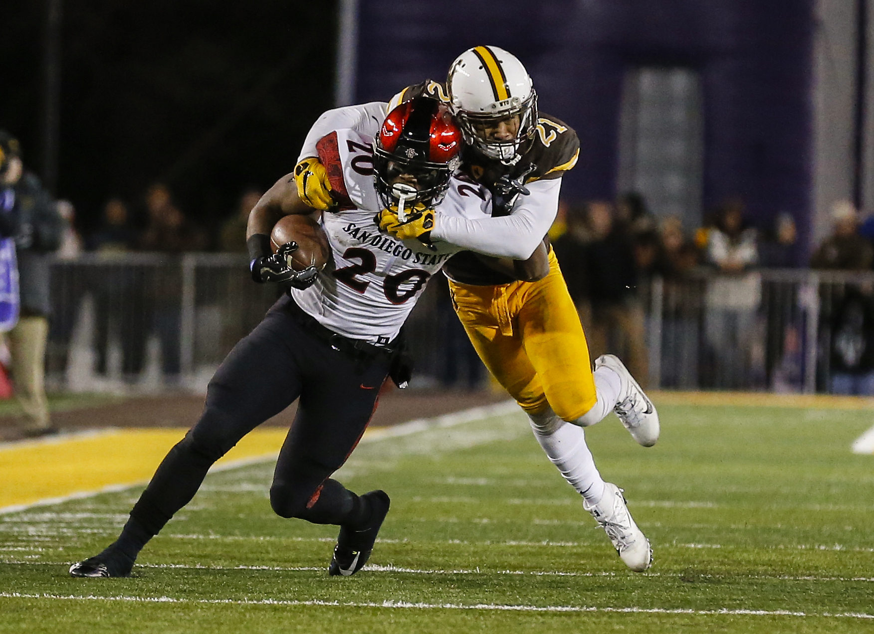 Dec 3, 2016; Laramie, WY, USA; San Diego State Aztecs running back Rashaad Penny (20) is tackled by Wyoming Cowboys cornerback Antonio Hull (21) during the second quarter at the Mountain West Championship college football game at War Memorial Stadium. Mandatory Credit: Troy Babbitt-Imagn Images