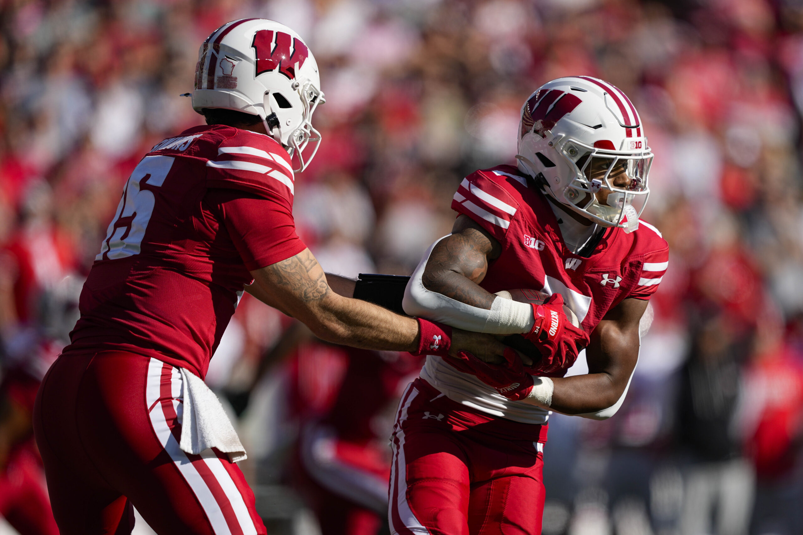 Oct 18, 2025; Madison, Wisconsin, USA;  Wisconsin Badgers quarterback Hunter Simmons (15) hands the football off to running back Dilin Jones (7) during the game against the Ohio State Buckeyes at Camp Randall Stadium. Mandatory Credit: Jeff Hanisch-Imagn Images