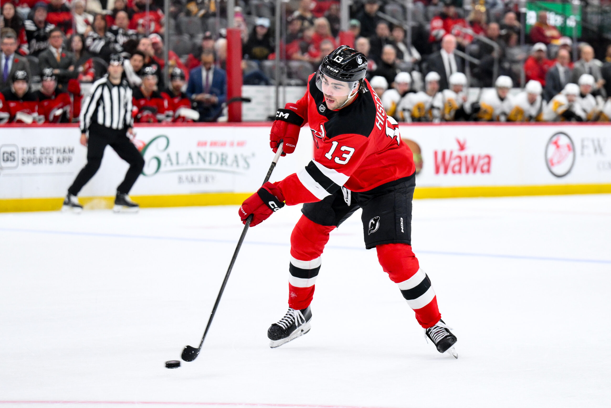 Nov 8, 2025; Newark, New Jersey, USA; New Jersey Devils center Nico Hischier (13) passes the puck against the Pittsburgh Penguins during the first overtime period at Prudential Center. Mandatory Credit: John Jones-Imagn Images